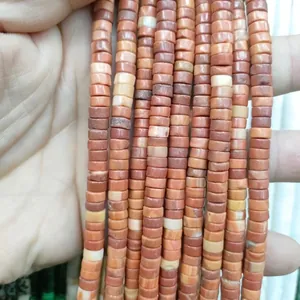 Macro shot of 3x6mm cylindrical jasper stone beads with natural red and yellow marble texture