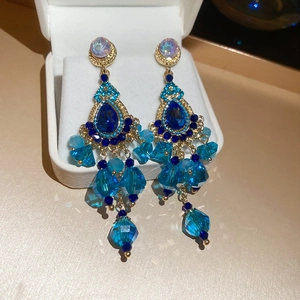 Detail of luxury crystal tassel earrings with blue pear-cut stones in gold setting