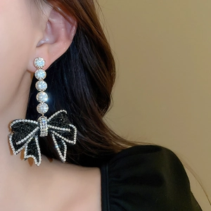 Close-up of elegant bow drop earrings with black and clear rhinestones on model