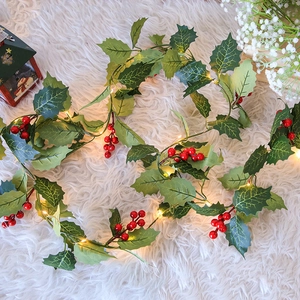 Artificial Christmas garland with red berries and LED lights on white faux fur background