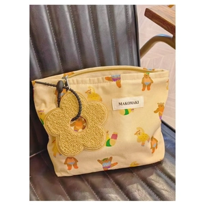 Detail of beige canvas makeup bag with cartoon bear print and yellow flower pendant