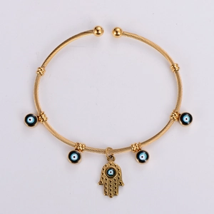 Detailed view of golden twisted cable Hamsa Hand bangle with blue Evil Eye charms