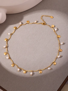 Detail of gold seashell necklace featuring freshwater pearls and lobster clasp