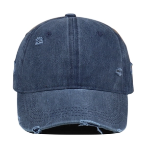 Close-up of distressed blue denim baseball cap showing vintage frayed holes and texture