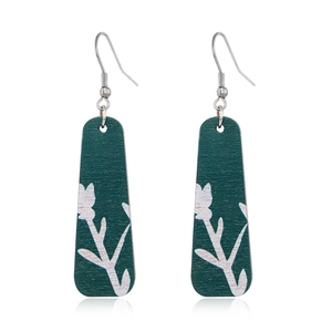 Detail of dark green wooden drop earrings featuring white botanical leaf patterns
