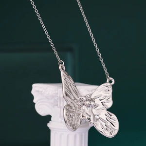 Polished silver butterfly necklace with titanium steel chain on white column decor