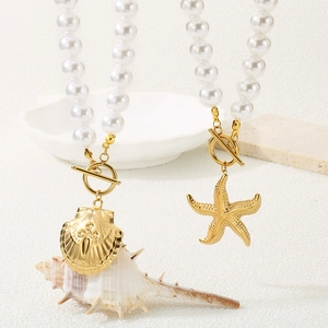 Detail of vintage pearl bracelets with gold starfish and scallop shell heart pendants
