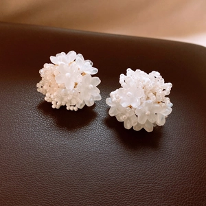 Macro detail of white flower stud earrings with translucent petals and bead clusters