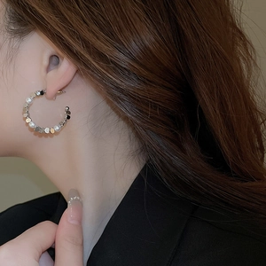Detail of C-shaped earring featuring alternating white pearls and silver metal discs