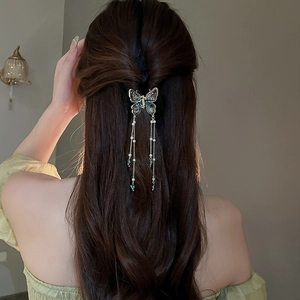 Detail of butterfly hair claw with pearls and long tassels on elegant half-up hairstyle