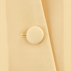 Close-up of light yellow twill fabric jacket featuring elegant fabric-covered buttons