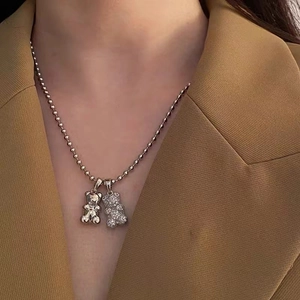 Dettaglio dei ciondoli a forma di orso con cristalli su una collana a catena con sfere