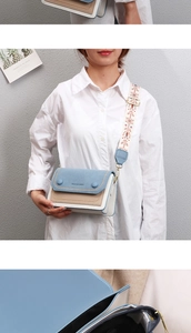 Detail of crossbody bag featuring wide embroidered strap and tricolor patchwork design