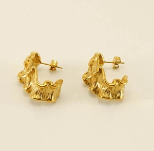 Macro shot of 18k gold plated C-shaped earrings with organic molten texture detail