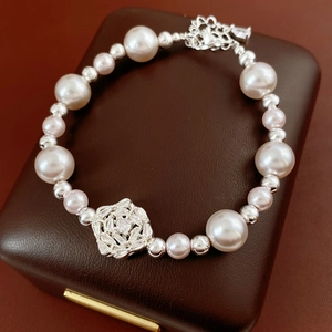 Macro shot of elegant pearl bracelet with zircon flower pendant on brown leather box