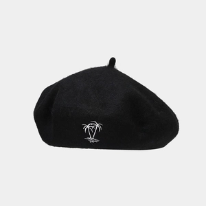 Detailed close-up of white palm tree embroidery on a black wool beret hat for women
