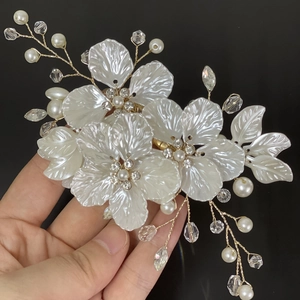 Macro shot of white shell petals, pearls and crystals on a bridal hair pin