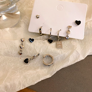 Detail view of heart-shaped silver earrings set with black enamel on a white card