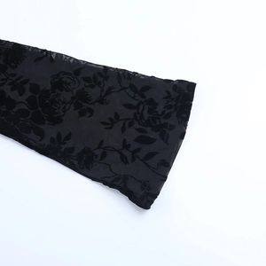 Détail du tissu en dentelle florale noire et texture en maille transparente sur la manche
