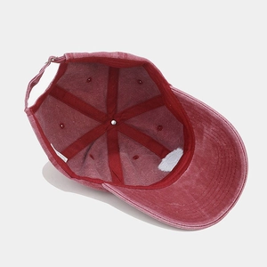 Detail view of red washed denim baseball cap interior with adjustable strap and care label