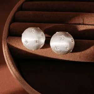 Boucles d'oreilles étoiles en argent brossé avec strass dans un écrin à bijoux.
