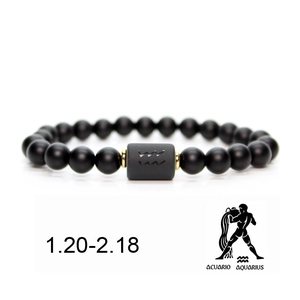 Detail of matte black onyx Aquarius zodiac bracelet with engraved silver charm and gold beads