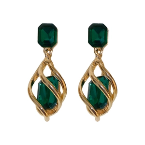 Vintage emerald green gemstone earrings with golden spiral metal frame on white background