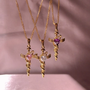 Three gold winged cross and snake necklaces with pink, white, and purple heart stones