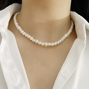 Close-up of elegant white freshwater pearl necklace on model in white shirt
