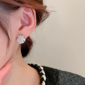 Detailed view of clustered pearl flower stud earring worn by a model on skin