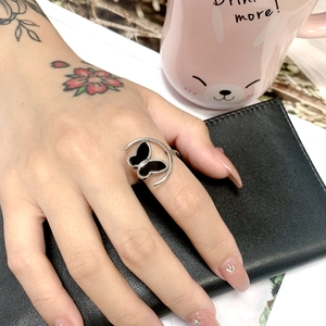 Detail of silver butterfly ring with black inlay worn on hand against dark leather