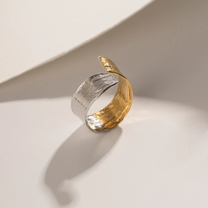 Detail of two-tone gold and silver minimalist ring with hammered texture and wavy design