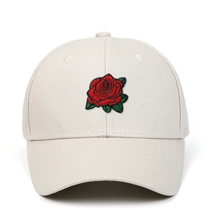 Détail de la broderie de rose rouge sur une casquette de baseball en coton beige à coutures