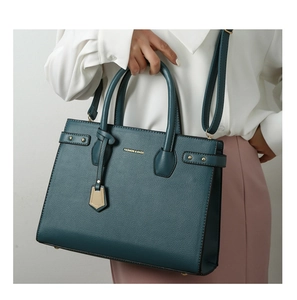 Macro view of dark green pebbled leather tote bag with gold lettering and adjustable strap