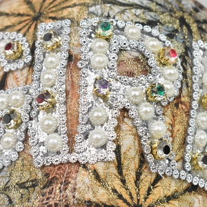 Close-up of colorful rhinestones and imitation pearls inlaid on printed baseball cap fabric