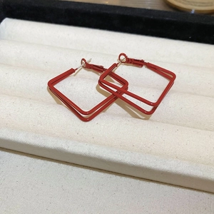 Macro shot of stylish red double-layered square hoop earrings on jewelry tray