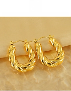 Close-up of twisted titanium steel hoop earrings with 18k gold plating on silk fabric