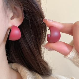 Detailed macro view of matte rose red C-shape stud earrings with frosted finish