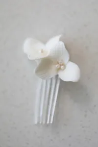 Detailed macro of white ceramic flower petals with fresh water pearls on bridal hair comb