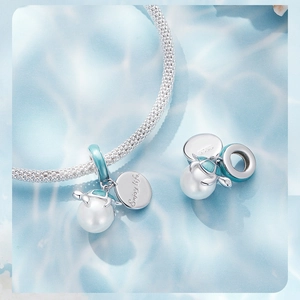 Close-up of S925 silver sea turtle charm with pearl and blue enamel on water background