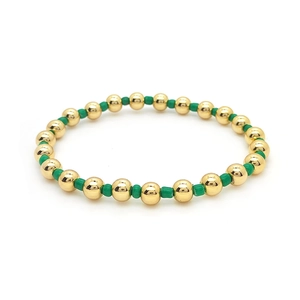 Detailed close-up of 18K gold-plated beads and green cylinder seed beads on elastic bracelet