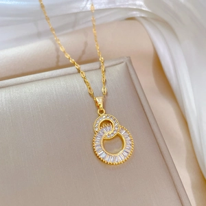 Close-up of golden double ring necklace with baguette and round cubic zirconia inlays