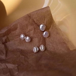 Three pairs of natural freshwater baroque pearl earrings on textured brown paper