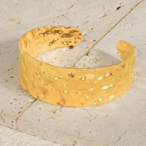Detailed view of wide 18k gold hammered texture open cuff bracelet on stone stand