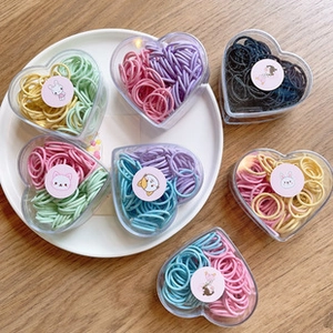 Detailed view of colorful elastic hair bands in heart-shaped boxes with cartoon stickers