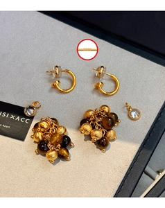 Macro detail of S925 silver hallmark on gold tiger eye and zircon tassel earrings