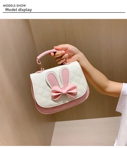Detail of cute pink bow and rabbit ears on quilted white PU leather child handbag