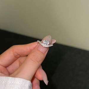 Macro shot of V-shaped silver ring featuring round-cut center stone and pave-set accents