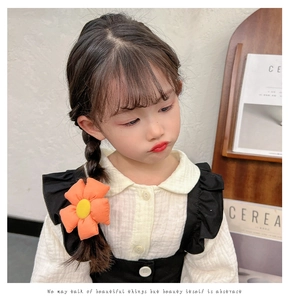 Detailed view of plush orange sunflower hair tie on child for cute ponytail styling