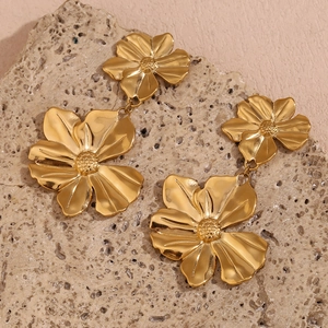 Detailed close-up of 18K gold plated double flower drop earrings on a stone surface